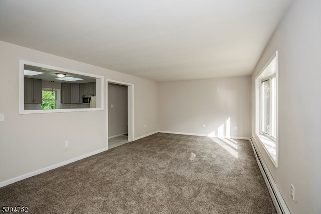 unfurnished room with a baseboard heating unit and carpet floors