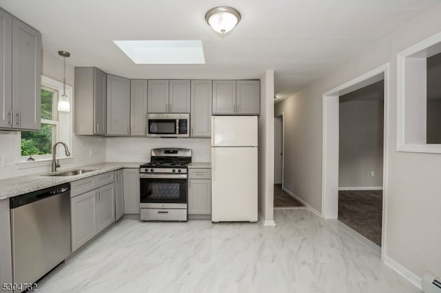 kitchen with appliances with stainless steel finishes, light stone countertops, a skylight, and light tile patterned floors