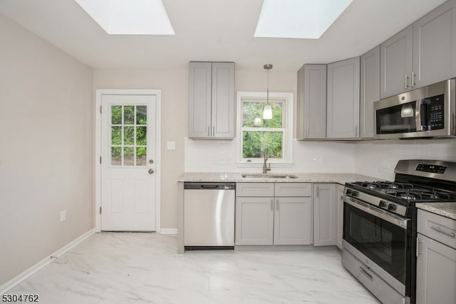 kitchen with stainless steel appliances, a skylight, sink, light tile patterned floors, and backsplash