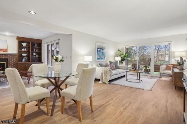 dining room featuring light hardwood / wood-style flooring and a brick fireplace