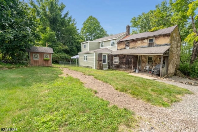 rear view of property featuring a patio, a yard, and a storage unit