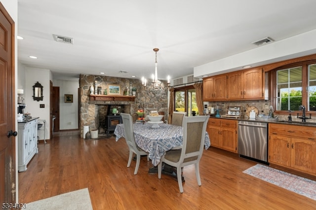 kitchen with light hardwood / wood-style floors, stainless steel dishwasher, sink, and a notable chandelier