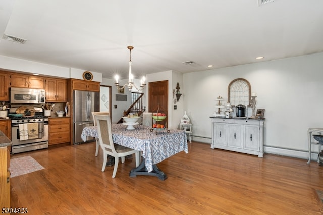 dining area with an inviting chandelier, baseboard heating, and light hardwood / wood-style flooring