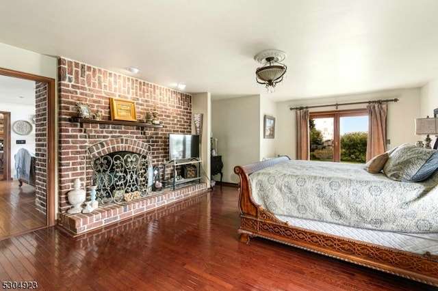 bedroom featuring wood-type flooring and a brick fireplace