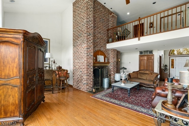 living room featuring a high ceiling, light hardwood / wood-style floors, and a fireplace