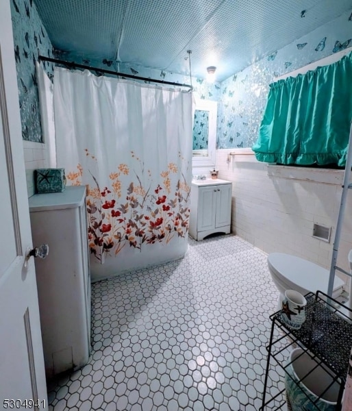 bathroom featuring vanity, toilet, and tile walls