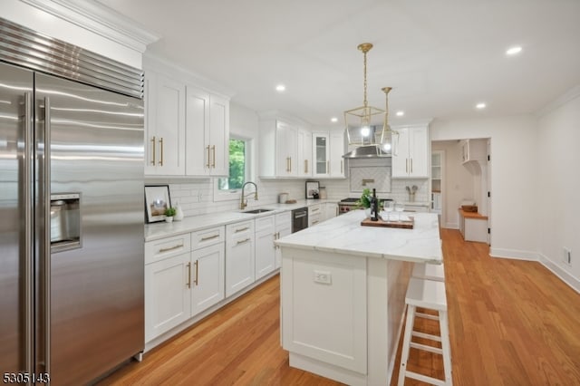 kitchen featuring built in refrigerator, sink, a center island, white cabinets, and light hardwood / wood-style floors