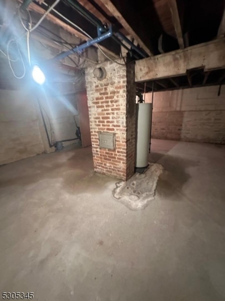 basement featuring gas water heater and brick wall