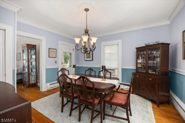 dining room featuring hardwood / wood-style floors, a baseboard heating unit, crown molding, and a chandelier