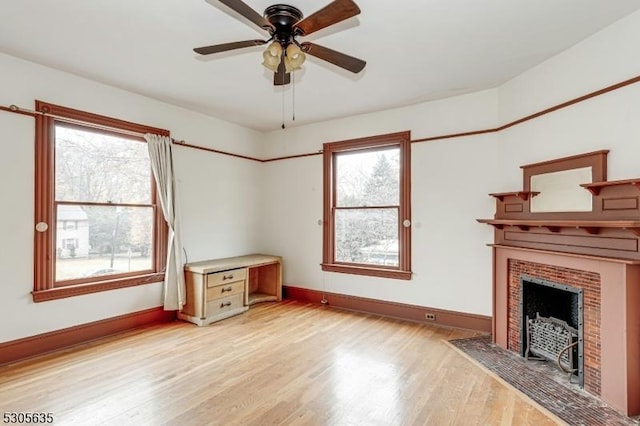 unfurnished living room with ceiling fan, light hardwood / wood-style floors, and a brick fireplace