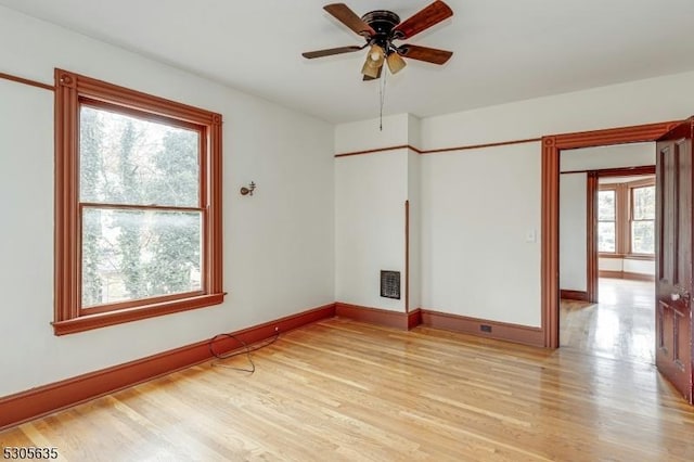 spare room featuring light wood-type flooring, ceiling fan, and a healthy amount of sunlight