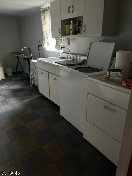 washroom featuring washing machine and dryer, sink, and cabinets