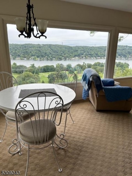 dining room featuring a chandelier, a water view, and carpet floors