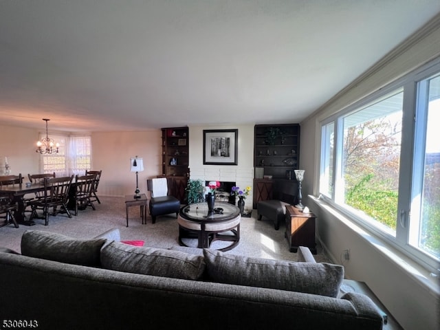 carpeted living room with ornamental molding, a chandelier, and a brick fireplace