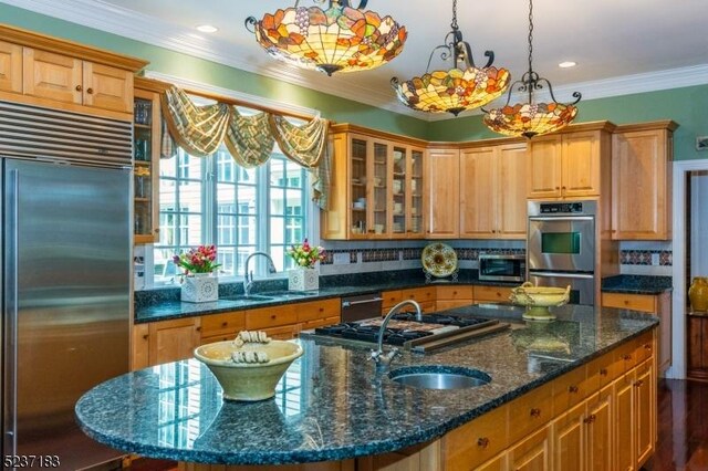 kitchen featuring appliances with stainless steel finishes, a kitchen island with sink, sink, and decorative light fixtures