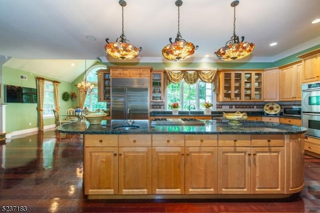 kitchen with stainless steel appliances, decorative light fixtures, and a kitchen island with sink