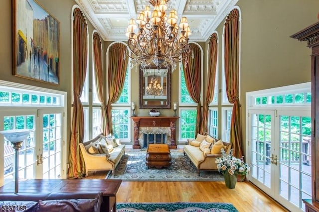 living area with a chandelier, coffered ceiling, a high end fireplace, crown molding, and french doors