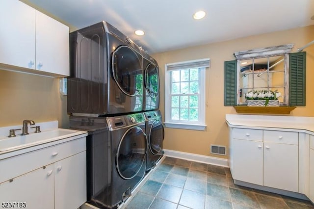 laundry room with cabinets, stacked washer / drying machine, and sink