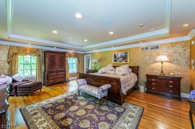 bedroom featuring multiple windows, a tray ceiling, and light hardwood / wood-style flooring