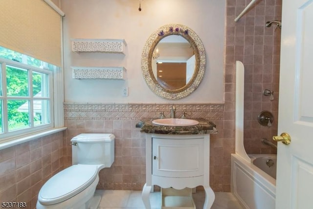 full bathroom with tiled shower / bath, vanity, toilet, and tile walls