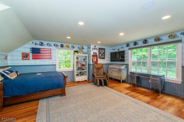 bedroom featuring lofted ceiling, wood-type flooring, and multiple windows