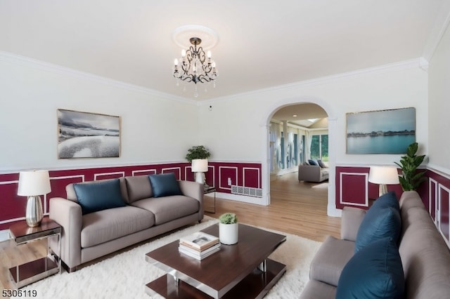 living room featuring a notable chandelier, light hardwood / wood-style flooring, and crown molding