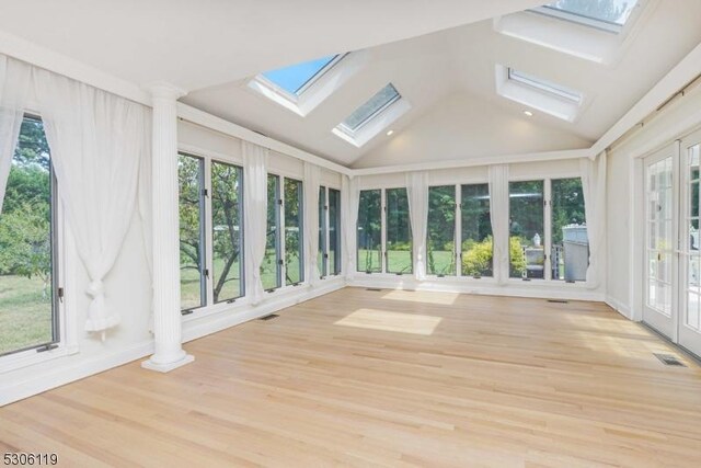 unfurnished sunroom featuring lofted ceiling with skylight and a healthy amount of sunlight