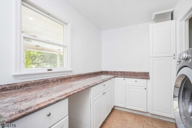 laundry area with washer / clothes dryer, light tile patterned flooring, and cabinets