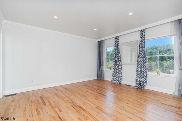 empty room with crown molding and light hardwood / wood-style flooring