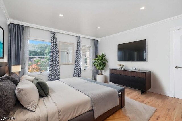 bedroom with ornamental molding and light hardwood / wood-style floors