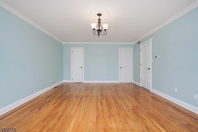 unfurnished room featuring light hardwood / wood-style flooring, ornamental molding, and an inviting chandelier