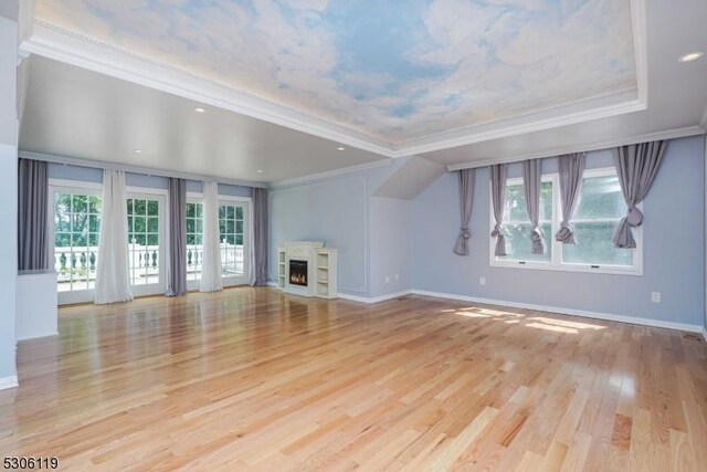 unfurnished living room featuring light wood-type flooring, ornamental molding, and a raised ceiling