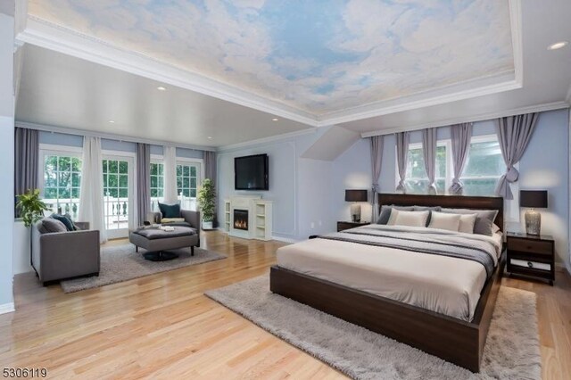 bedroom with ornamental molding, a raised ceiling, and light hardwood / wood-style floors