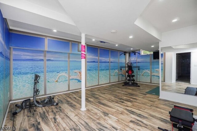 workout area with expansive windows, a water view, and wood-type flooring