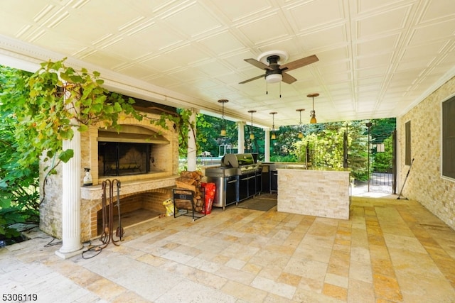 view of patio with an outdoor stone fireplace, ceiling fan, and area for grilling