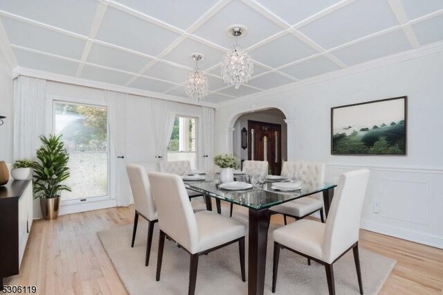 dining space with a notable chandelier, coffered ceiling, and light hardwood / wood-style floors