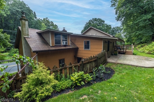 back of property featuring a patio area, a wooden deck, and a lawn