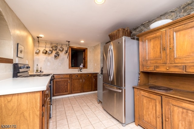 kitchen with light tile patterned flooring, range with electric stovetop, and stainless steel refrigerator