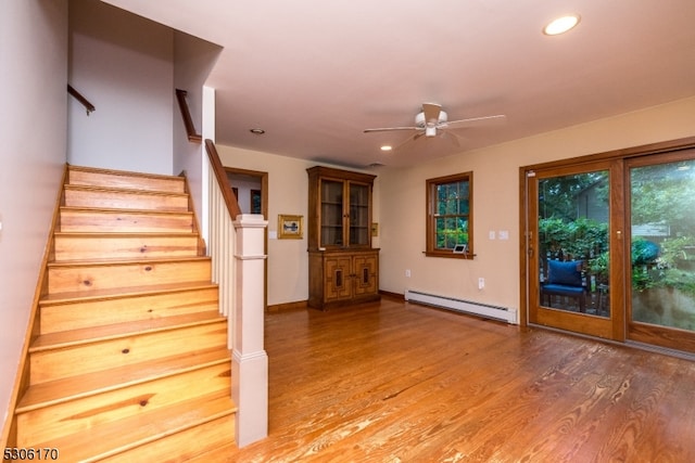 stairway with ceiling fan, hardwood / wood-style flooring, and baseboard heating