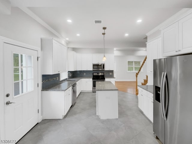 kitchen with hanging light fixtures, appliances with stainless steel finishes, a healthy amount of sunlight, light hardwood / wood-style floors, and a center island