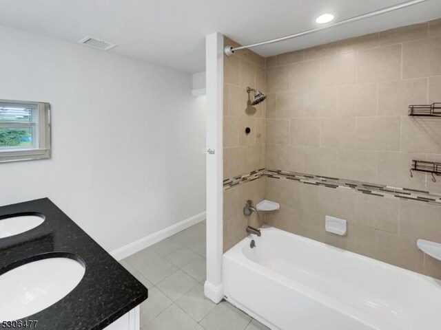 bathroom with double sink vanity, tile patterned flooring, and tiled shower / bath