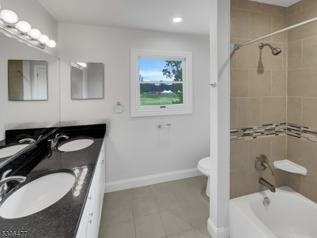 full bathroom with double sink vanity, toilet, tiled shower / bath combo, and tile patterned flooring