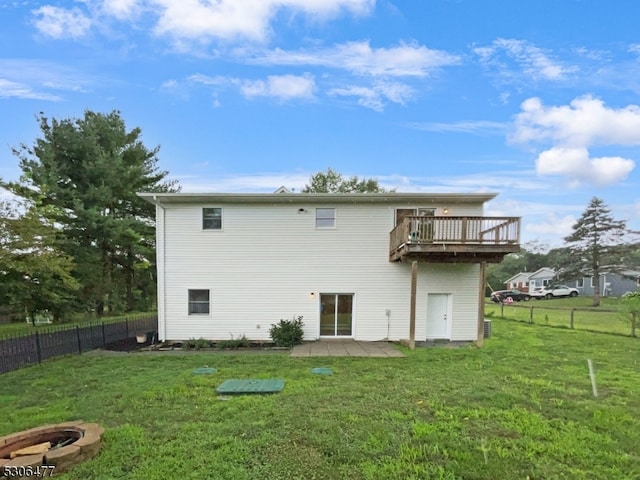 back of house featuring a yard, a wooden deck, and a fire pit