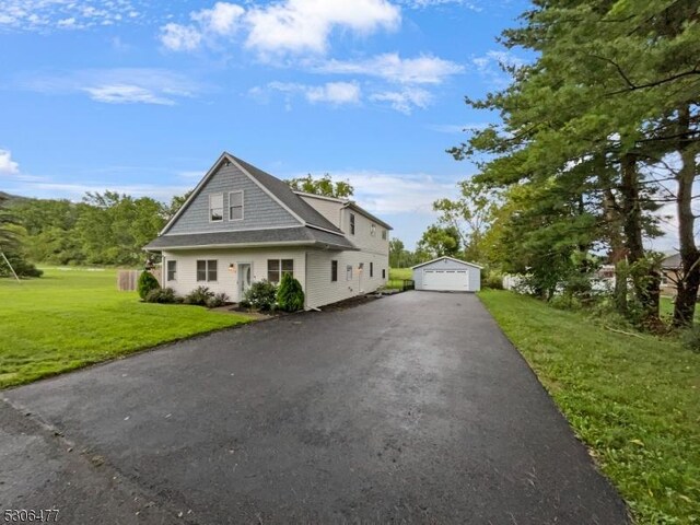 view of front of property with a garage, an outbuilding, and a front lawn