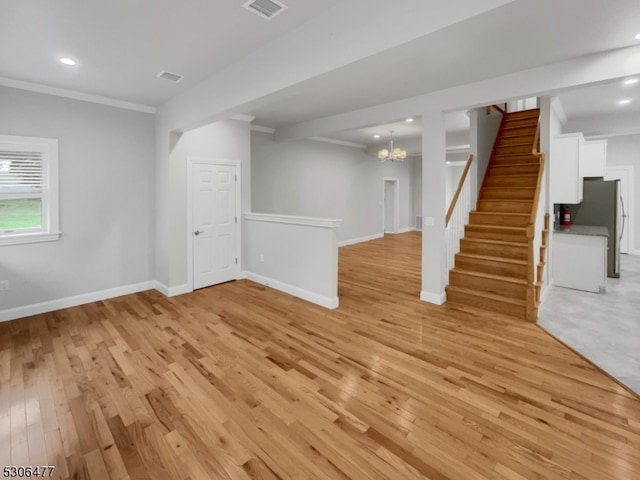 basement featuring a notable chandelier, light hardwood / wood-style flooring, and stainless steel refrigerator