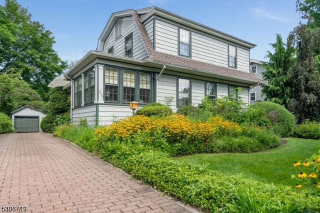 view of side of property with a garage, an outbuilding, and a lawn