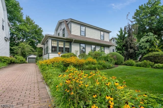 view of front of house with a front lawn, an outdoor structure, and a garage