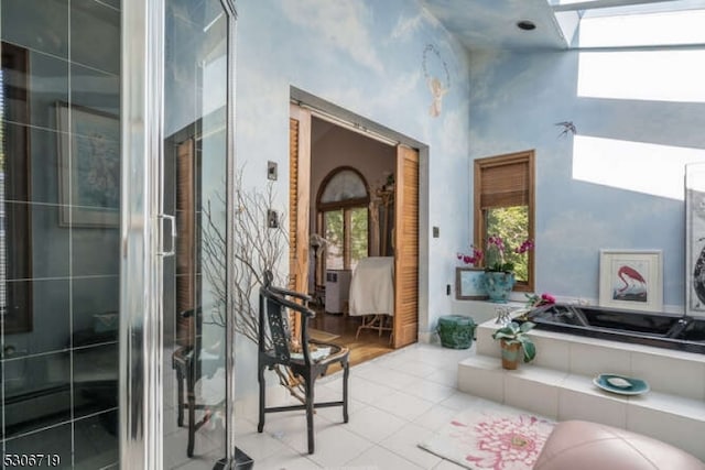 bathroom with tile patterned floors, a washtub, a skylight, and a high ceiling