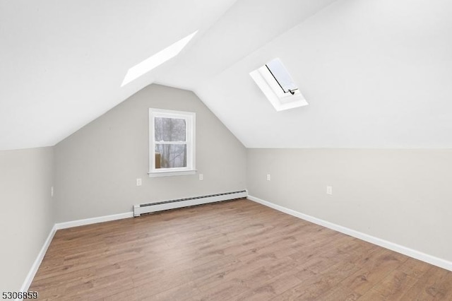 bonus room with light hardwood / wood-style floors, a baseboard heating unit, and vaulted ceiling with skylight