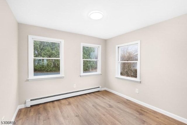 unfurnished room featuring light hardwood / wood-style flooring and a baseboard heating unit